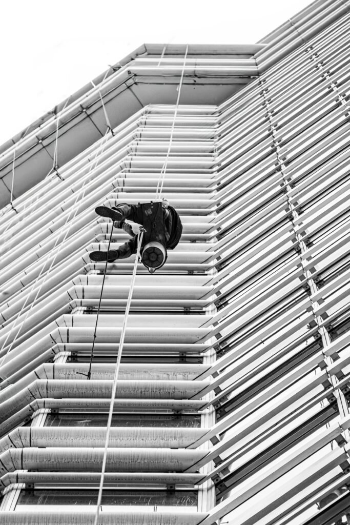 A monochrome view of a high-rise worker suspended on the side of a building in Buenos Aires.